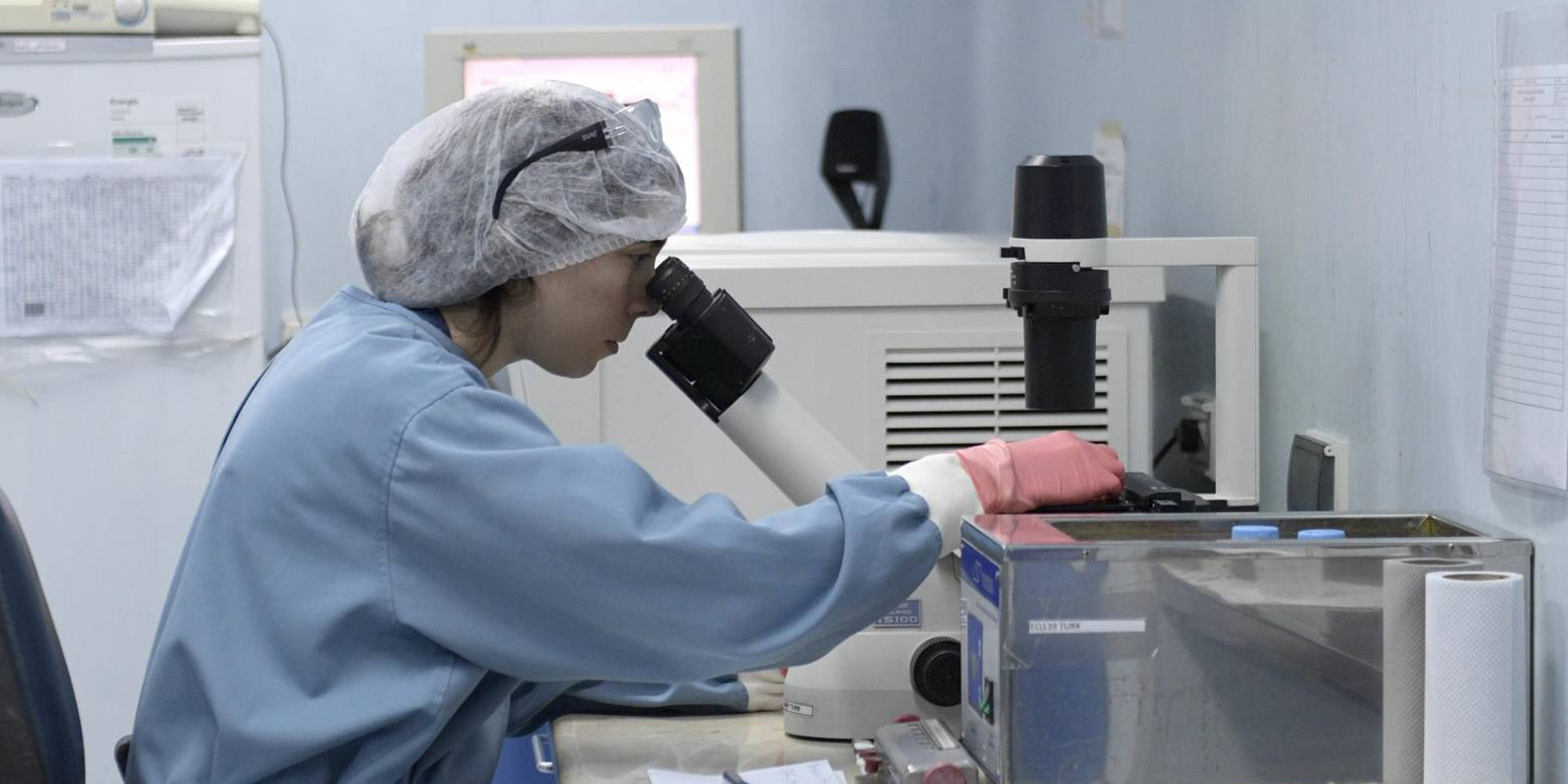 Eine Frau schaut durch ein Mikroskop