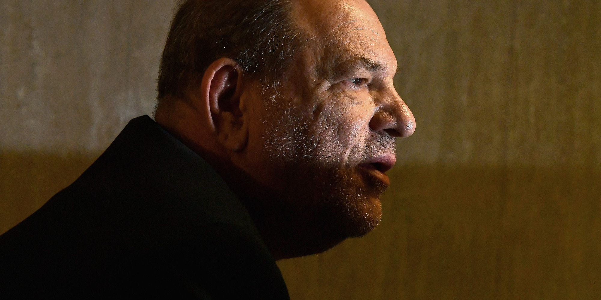 Harvey Weinstein vor Gericht, sein Gesicht ist halb im Schatten.