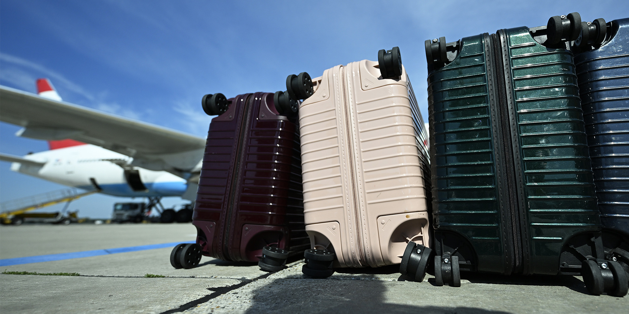 Flugzeug im Hintergrund, Koffer am Boden im Vordergrund